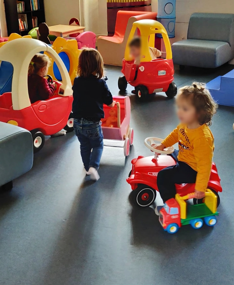 Enfants qui jouent avec des porteurs et des petites voitures dans l'espace jeux